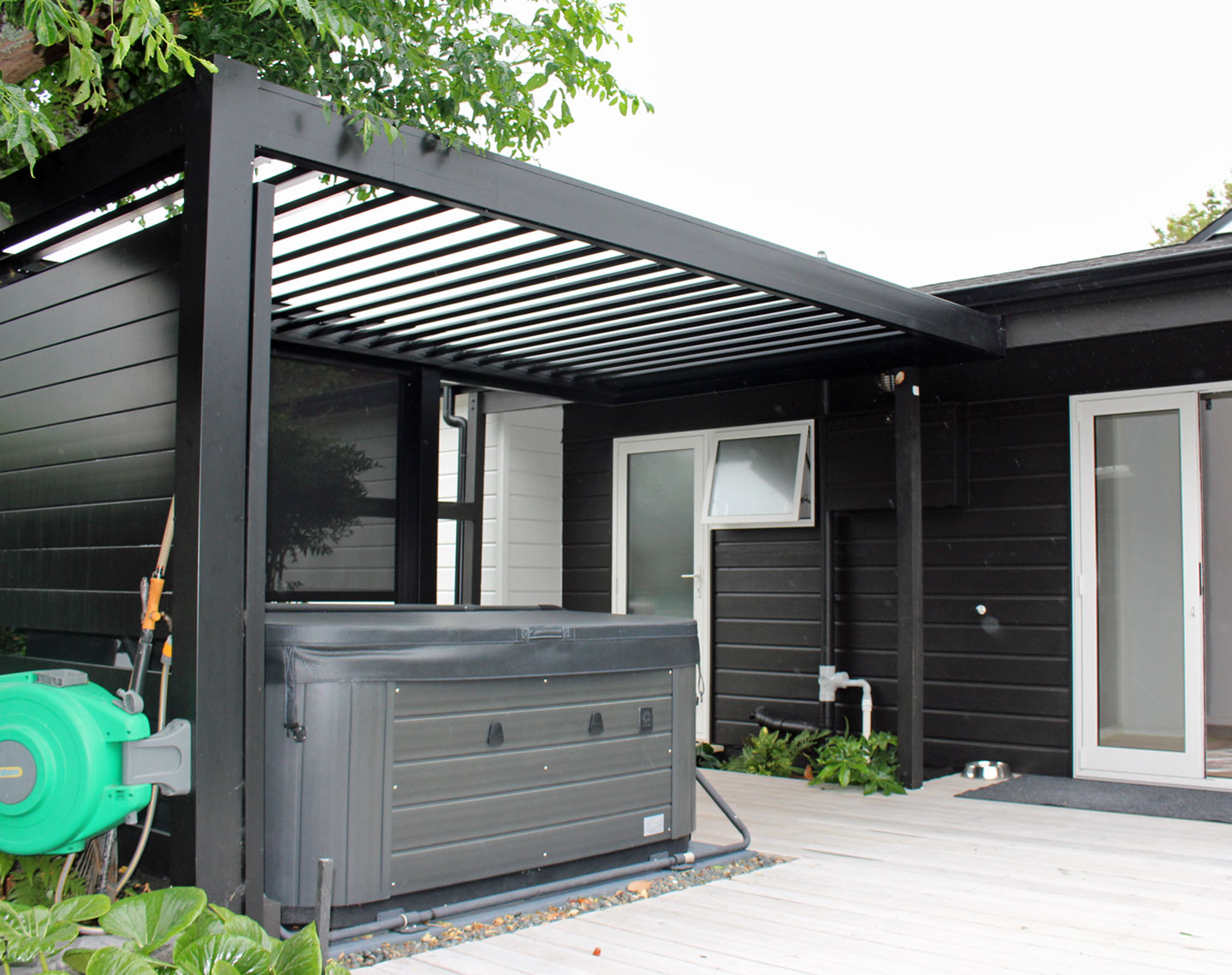 Bask louvre roof with matching slat windbreak as spa shelter on back deck